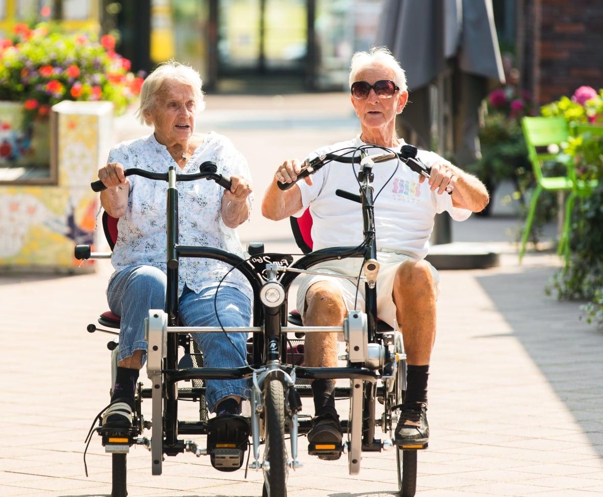 Two elderly folks riding a tandem bike